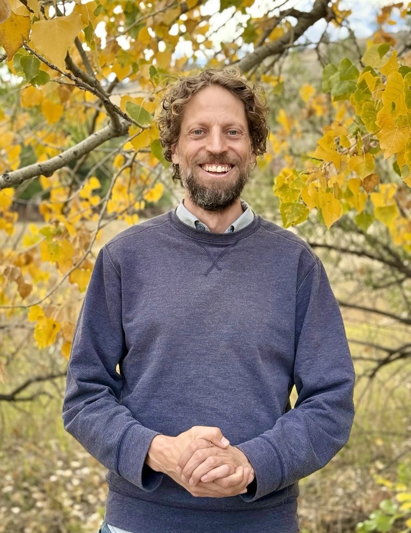 Jason Digges smiling outdoors beneath autumn trees